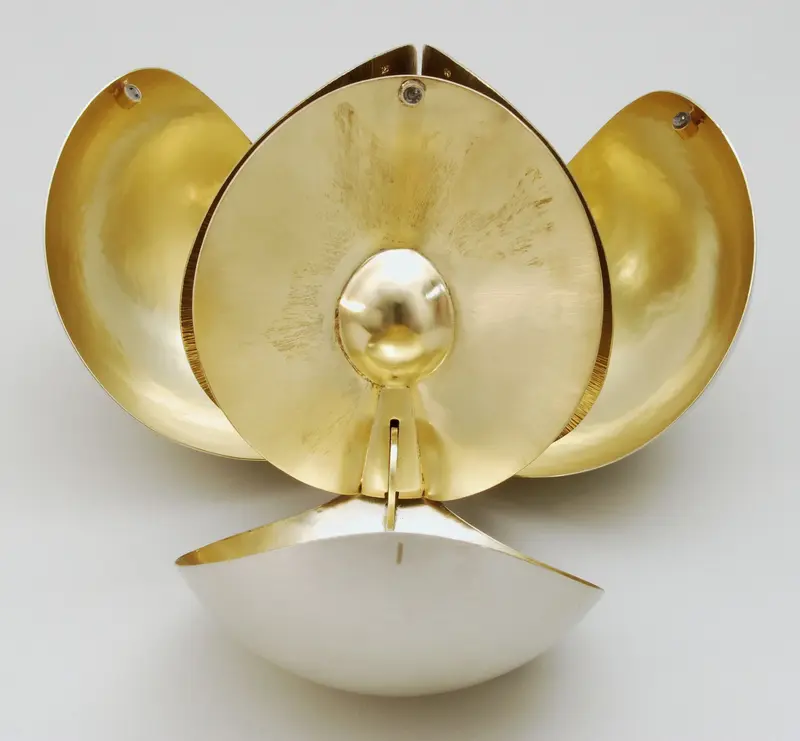 Weißes Metall-Objekt ähnlich einer Blume, innen vergoldet