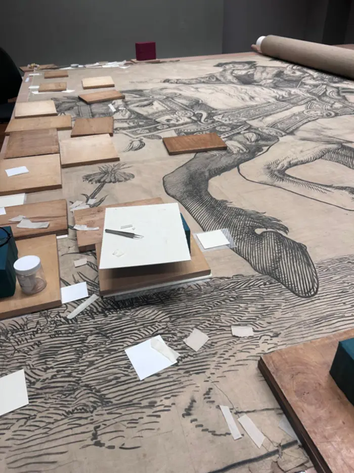 Die Zeichnung eines Pferdes mit Reiter, darauf befinden sich Arbeitsutensilien.