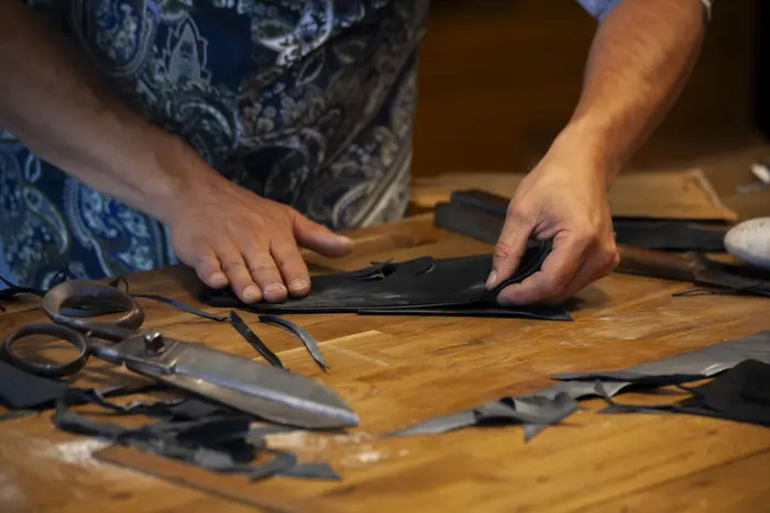 Hände an einem Tisch voll mit Stoffen und einer großen Schere